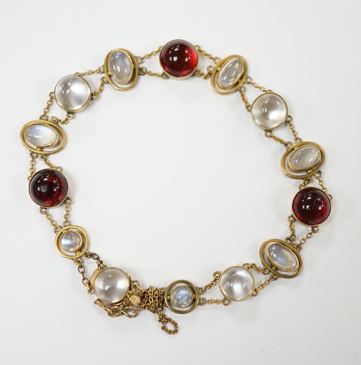 A George V 9ct, cabochon moonstone and cabochon red paste set bracelet, 16.5cm, gross weight 12 grams, Condition - fair